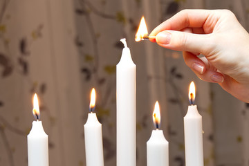 Five burning candles. woman hand lights candles Romantic atmosphere. Nice decoration.