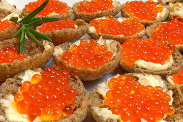 Sandwiches with red caviar on white palte close up