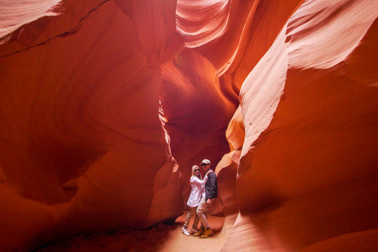 Happy moslem couple exploring inside the Grand Canyon, eroded sandstone rock in slot canyon, antelope valley, page, arizona, usa.  - Powered by Adobe
