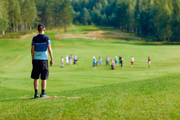 a man standing on a huge green field of golf, amid many other people