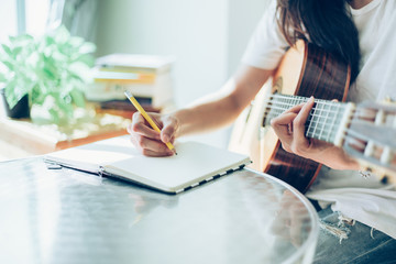 artist songwriter thinking writing notes,lyrics in book at studio.man playing live acoustic guitar...
