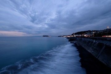 evening of coastline in Kamakura Japan. Sea waves against coast. Cloudy sunset sky. Wide angle and long exposure