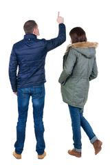 Back view of couple couple in winter jackets pointing.