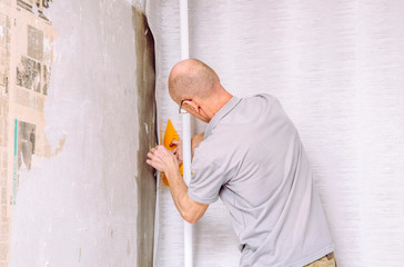 Man hanging a minimalist gray pattern paper wallpaper on wall. Lot of room for copy space.