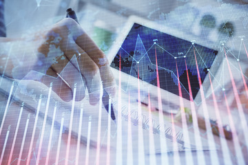 Financial forex graph drawn over hands taking notes background. Concept of research. Multi exposure