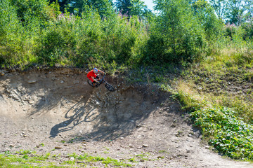 Mountain biker riding on bike in summer mountains forest landscape. Man cycling MTB flow trail track.