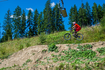 Mountain biker riding on bike in summer mountains forest landscape. Man cycling MTB flow trail track.