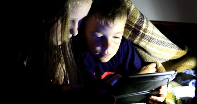 Little girl and boy watching content on her smartphone. The pitfalls of social networks. The childern secretly communicates over the Internet at night. Viewing inappropriate content.