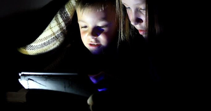 Little girl and boy watching content on her smartphone. The pitfalls of social networks. The childern secretly communicates over the Internet at night. Viewing inappropriate content.