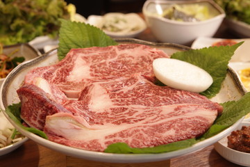 Two pieces of fillet meat are placed on a plate with sesame leaves and onions(두조각의 등심고기가 양파와 깻잎과 함께 접시에 담겨 있다)
