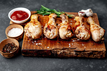 grilled chicken legs with spices on a cutting board on a stone background