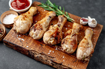grilled chicken legs with spices on a cutting board on a stone background