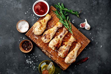 grilled chicken legs with spices on a cutting board on a stone background