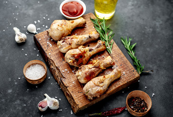 grilled chicken legs with spices on a cutting board on a stone background