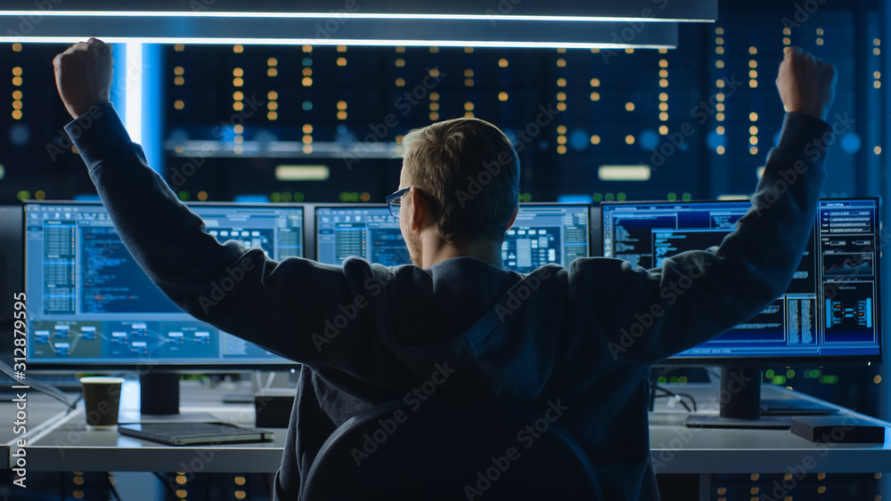 Poster IT Specialist Working on Personal Computer with Monitors Showing Coding Language Program, He Celebrates His Success by Doing YES Gesture. Technical Room of Data Center.