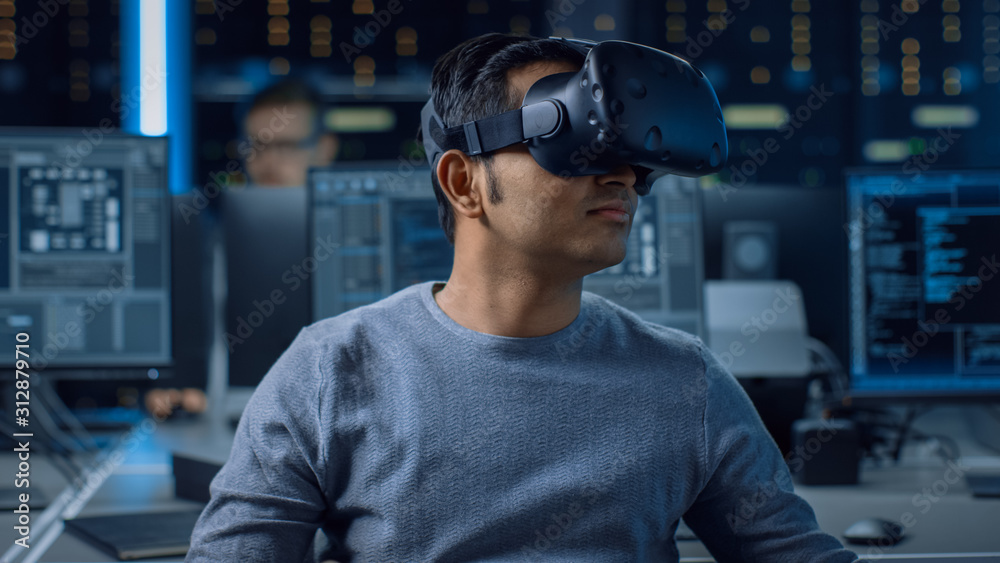 Aufkleber Software Delevoper Wearing Virtual Reality Headset on His Head, Developing and Programming VR Game or Application. In the Background Technology Developing Studio with Computers and Monitors