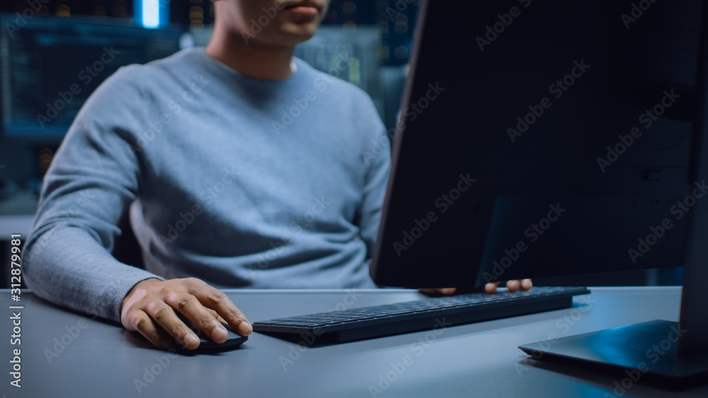 Poster Portrait Shot of Anonymous Software Developer Sitting at His Desk and Working on Computer in Digital Identity Cyber Security Data Center. Hacking or Programming.