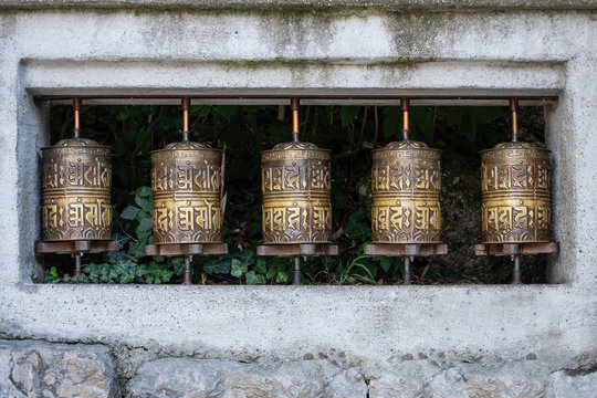 Five old prayer wheels with plants