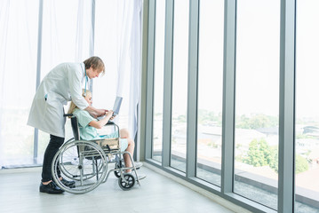 Fototapeta na wymiar Doctor talking to woman in wheelchair after surgery