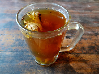 A glass of hot sweet ginger tea (teh manis jahe panas) on the wooden table