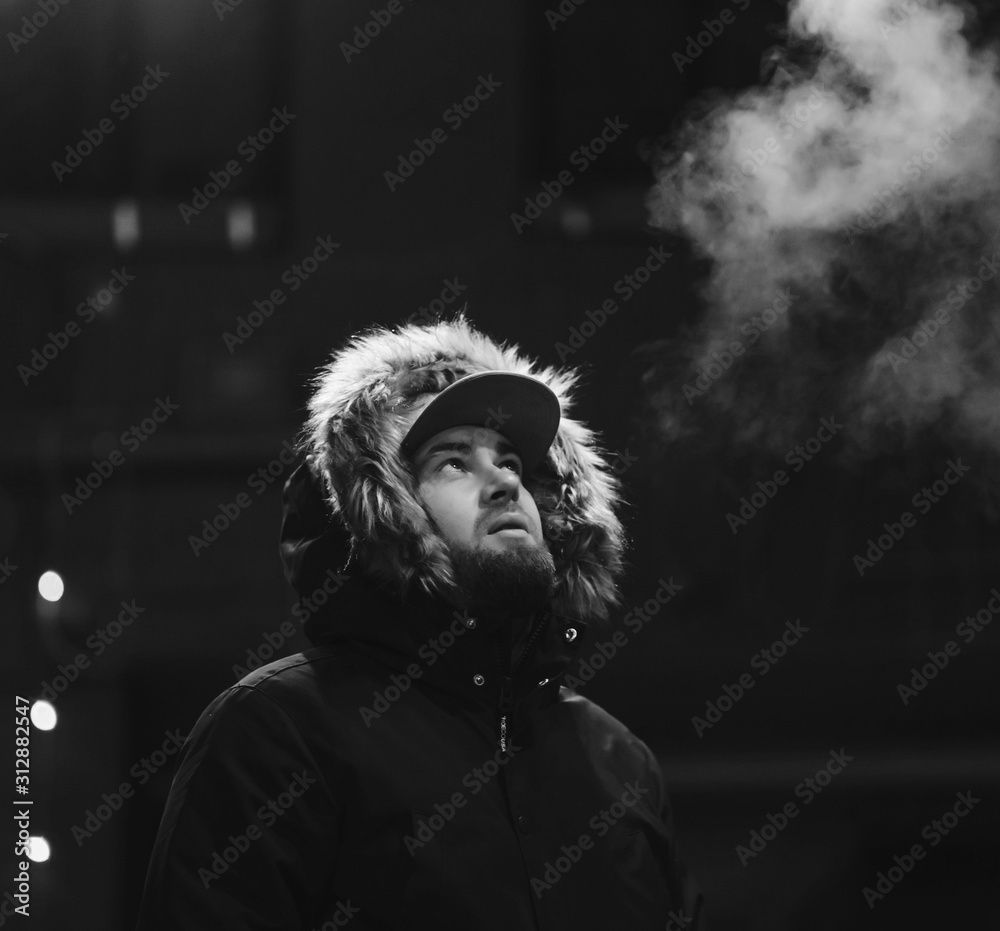 Wall mural bearded man smoking against the background of the night city