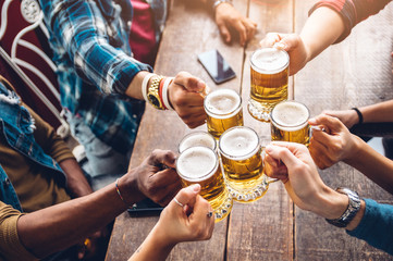 Group of people enjoying and toasting a beer in brewery pub - Friendship concept with young people having fun together - obrazy, fototapety, plakaty