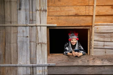 Fotobehang Tourists wearing hill tribe clothes. An Akha on the window. Tourists wearing Hmong hill tribe clothes and sitting with mobile, by window. © Thirawatana