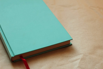 Book cover with blank space for inscription. book with turquoise cover and red bookmark on kraft paper.