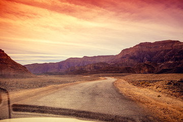 Driving a car on a mountain road in the desert. View of sandstone mountains through the windscreen....