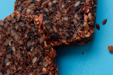 Sliced whole grain bread rye with seeds flax, sunflower, pumpkin and sesame.Healthy food, eco-friendly natural products. Fresh bread on a blue background.