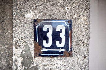 Number 33, thirty-three, street number sign on the wall