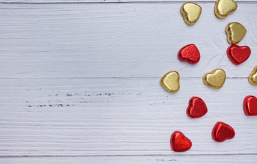 valentine day concept. mini hearts red and gold color on white wood texture background