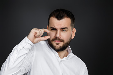 Obraz premium handsome bearded man holding two hands in front of him showing small size on black background