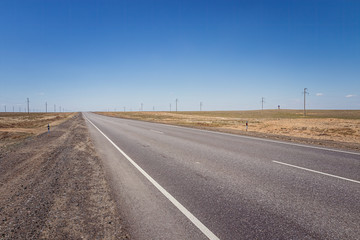 Modern two-lane asphalt desert road against a blue sky in Kyzylorda Oblast of Kazakhstan