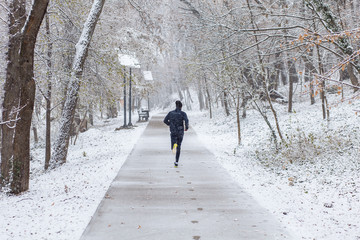 Young man running in city park at cold winter day.	