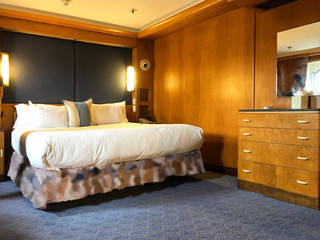 Bedroom inside luxury first class stateroom or cabin or suite with king or queen bed on historic...