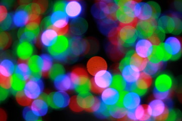 Christmas or New Year defocused lights, bokeh background. Beautiful blurred circles of green, blue, red colors on black background, winter holidays concept.