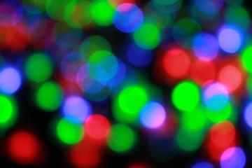 Fototapeta premium Christmas or New Year defocused lights, bokeh background. Beautiful blurred circles of green, blue, red colors on black background, winter holidays concept.