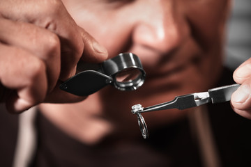 Professional jeweler evaluating beautiful ring, closeup view