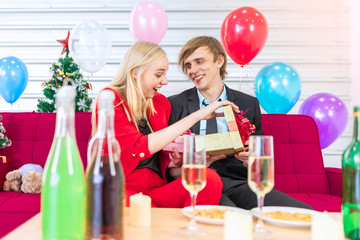 Young handsome man make a surprise with a present to his prety grilfriend in new year celebrate party