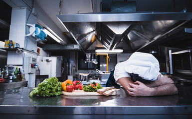 Tired chef worker fall asleep during working hours in the kitchen of a restaurant