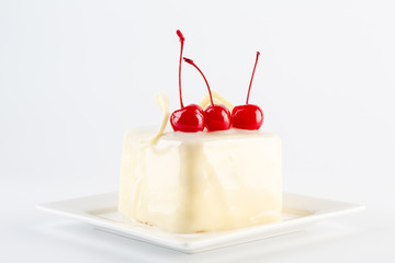 Modern white chocolate cake with red cherry on plate