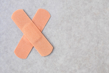 A two medical plasters of cross shape on neutral background. Patches from injury.