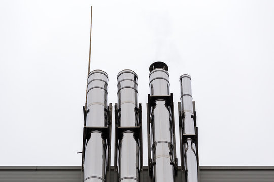 Chrome ventilation pipes on the outside wall of the white and blue Industrial building