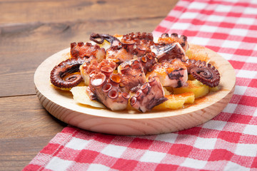 Pulpo a la gallega, galician octopus with potatoes, paprika, salt and olive oil.  typical Spanish Galician tapa, on a traditional wooden plate. Tipical Spanish tapa concept.