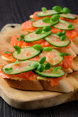Sandwich with salmon on wooden plate