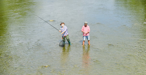 one team. father and son fishing. adventures. recreation and leisure outdoor. hobby and sport activity. Trout bait. two happy fisherman with fishing rod and net. Big game fishing. male friendship