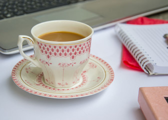 Coffee in the office, close-up of the desk with beautiful decorated cup with hot beverage, business concept