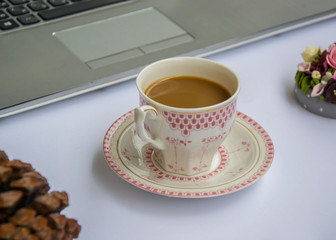 Coffee in the office, close-up of the desk with beautiful decorated cup with hot beverage, business concept