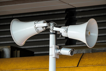 two white loudspeakers and security camera on pole in a public place. providing security in the city, notification of emergencies, informing passengers, technical means of notification and control